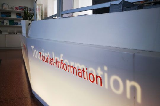Touristeninformationsschalter mit Broschüren in heller Lobby.